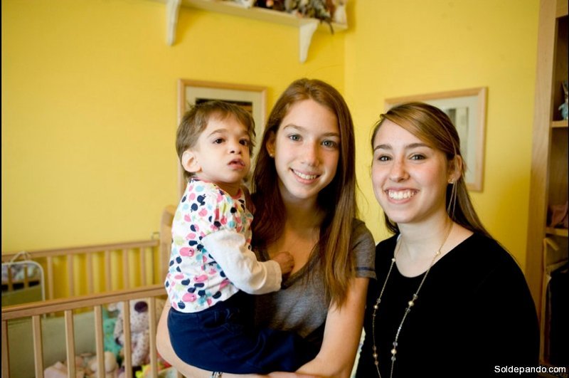 En brazos de su hermana menor, Carly, junto a la hermana mayor Caitlin.